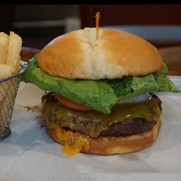 A juicy cheeseburger with lettuce, tomato, and onion, served with a side of fries.