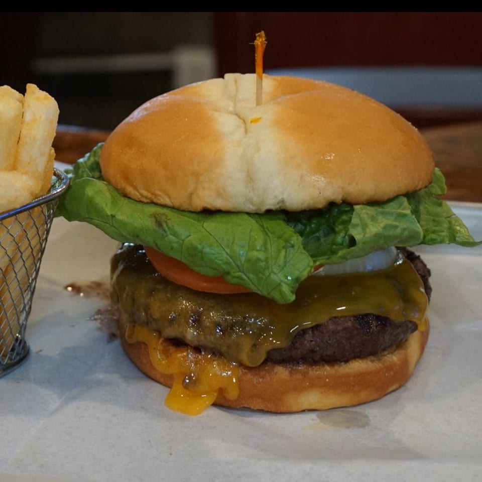 A juicy cheeseburger with lettuce, tomato, and onion, served with a side of fries.